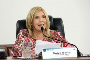#PraCegoVer: Foto mostra a presidente da Câmara, vereadora Dalva Berto, sentada em seu lugar, segurando um documento e discursando para o público.