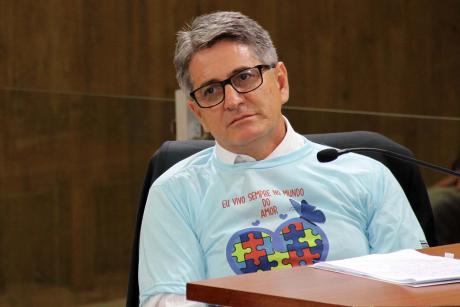 #PraCegoVer: Foto do vereador Aguiar sentado em seu lugar, acompanhando a sessão ordinária. Ele usa uma camiseta alusiva ao Dia Mundial da Conscientização do Autismo.
