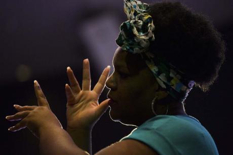 #PraCegoVer - Uma intérprete de Libras se comunica usando as mãos e a expressão facial