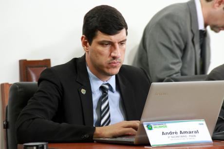 #PraCegoVer: Foto mostra o vereador André Amaral sentado em seu lugar no plenário, mexendo em um notebook.