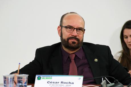 #PraCegoVer: Foto mostra o vereador César Rocha (Rede) sentado em seu lugar no plenário, prestando atenção na sessão ordinária.