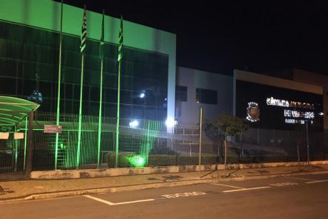#PraCegoVer: Foto mostra a fachada da Câmara durante a noite, iluminada na cor verde. 