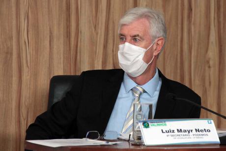 #PraCegoVer: Vereador Mayr, usando uma máscara, acompanha a sessão sentado em sua tribuna