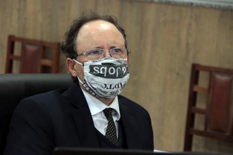 #PraCegoVer: Vereador Henrique Conti acompanha a sessão de sua tribuna na Câmara. Ele usa uma máscara com estampas de manchetes de jornais. 