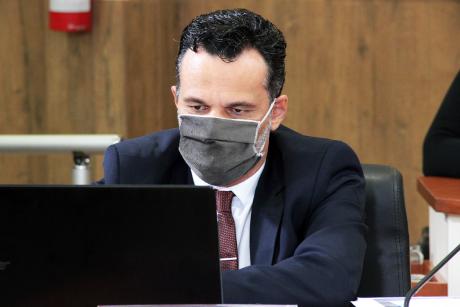 #PraCegoVer: Vereador Giba lê algo em seu computador portátil durante a sessão. Ele usa uma máscara marrom. 