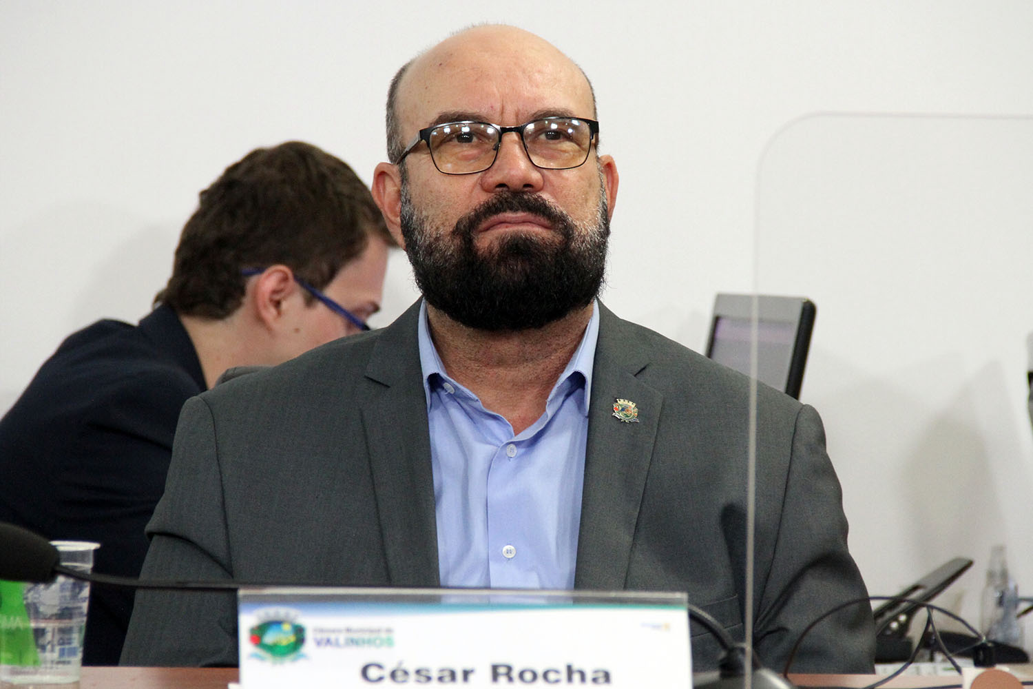 #PraCegoVer: foto mostra o vereador César Rocha em seu lugar no plenário, acompanhando a sessão ordinária.